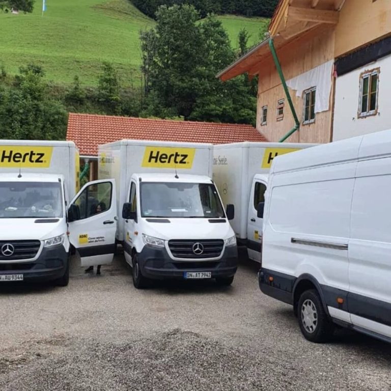 Drei weiße Transporter stehen in einer ländlichen Umgebung.